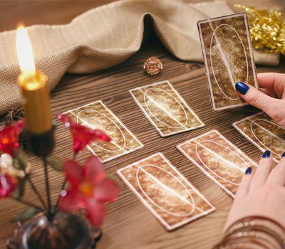 A person is playing tarot cards on a wooden table