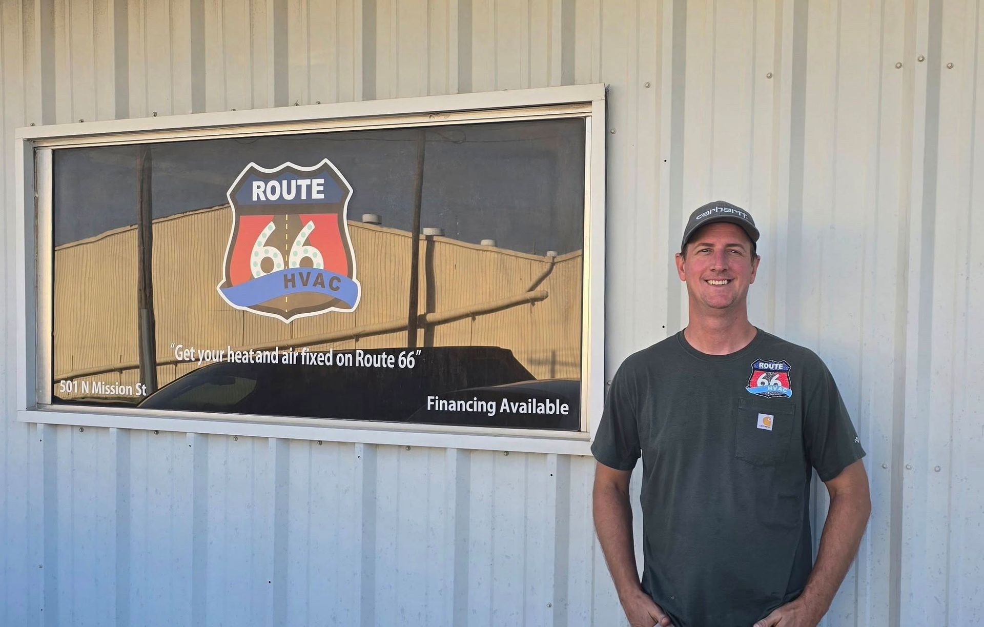 Man standing by Route 66 HVAC sign on a building.