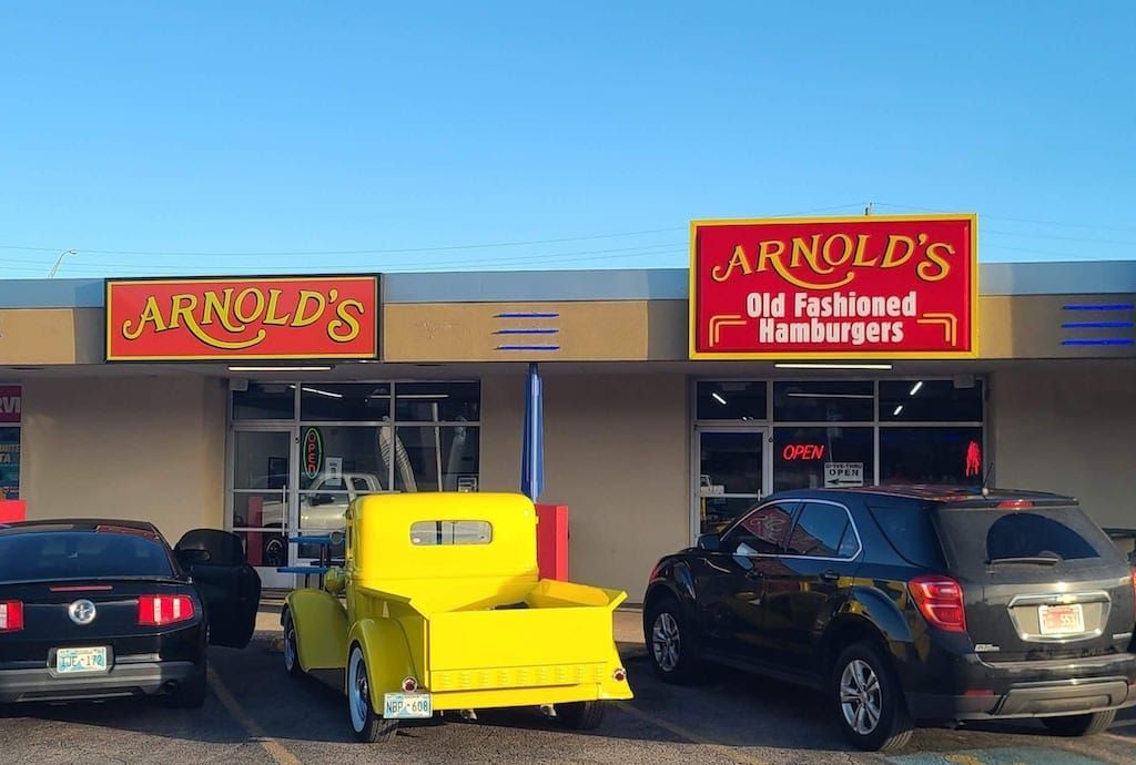 Arnold's Old Fashioned Hamburgers restaurant storefront with red signs; a yellow truck and cars parked in front.