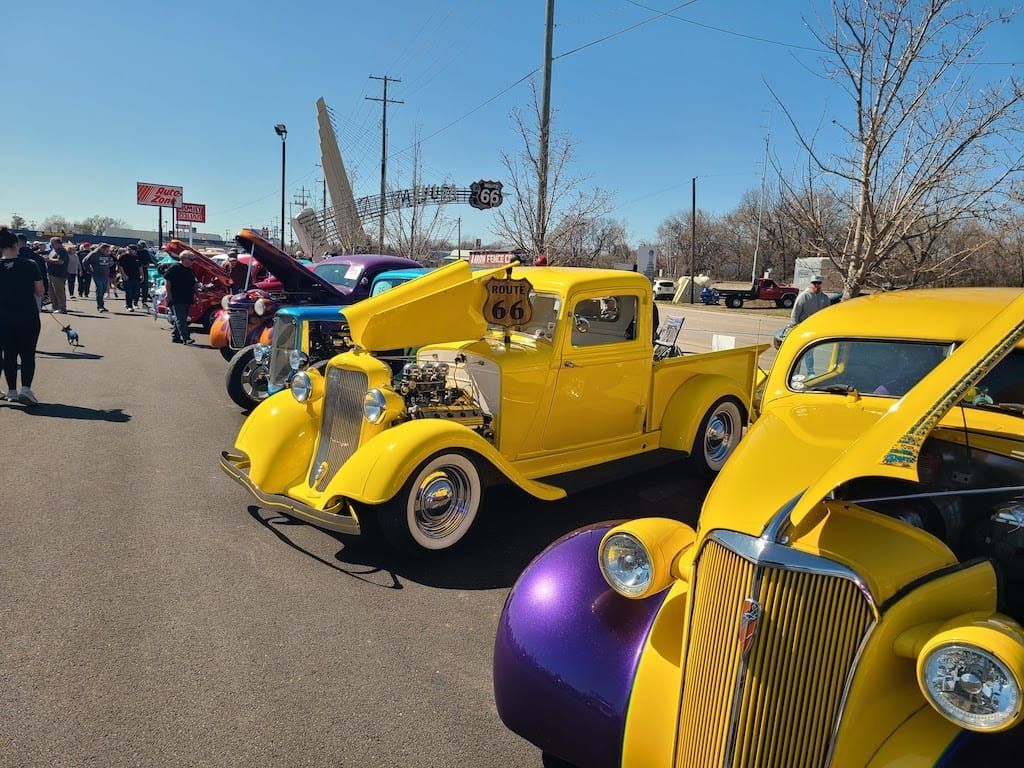 Classic cars on display in a sunny outdoor setting; yellow vehicles are prominent.