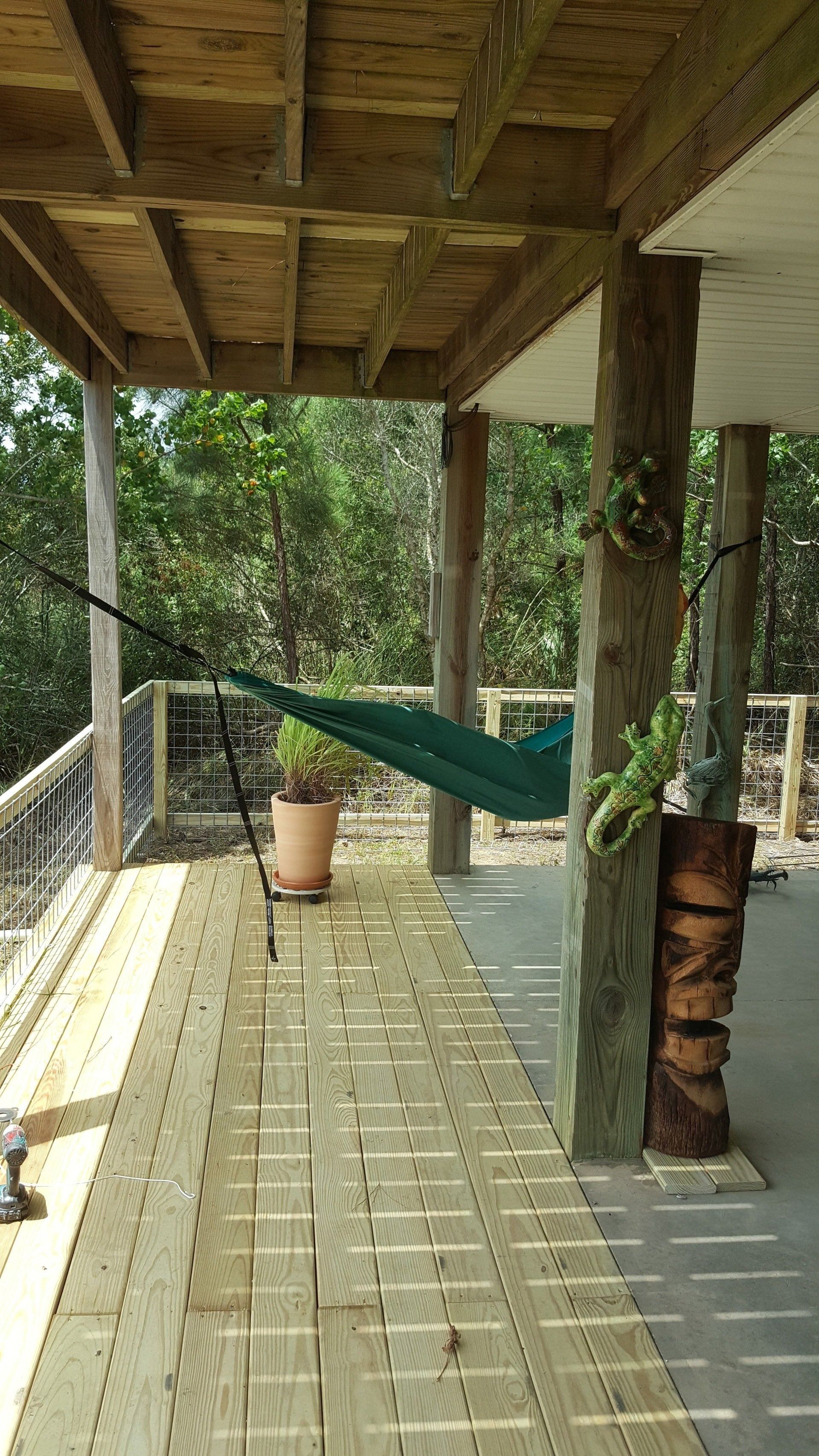 Wooden deck with hammock, greenery, and lumber supports.