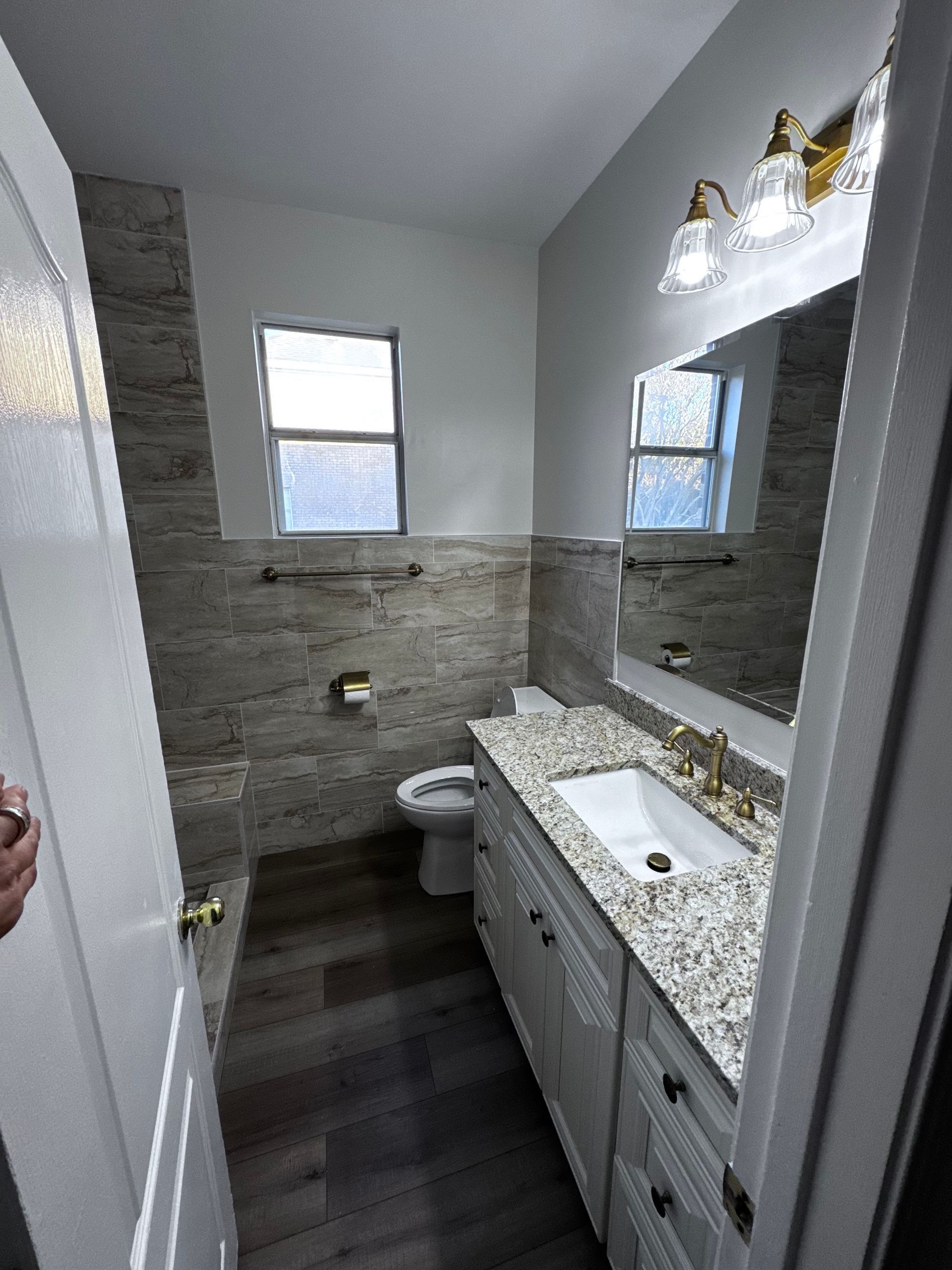 Bathroom with a vanity, toilet, and tiled walls and floor.