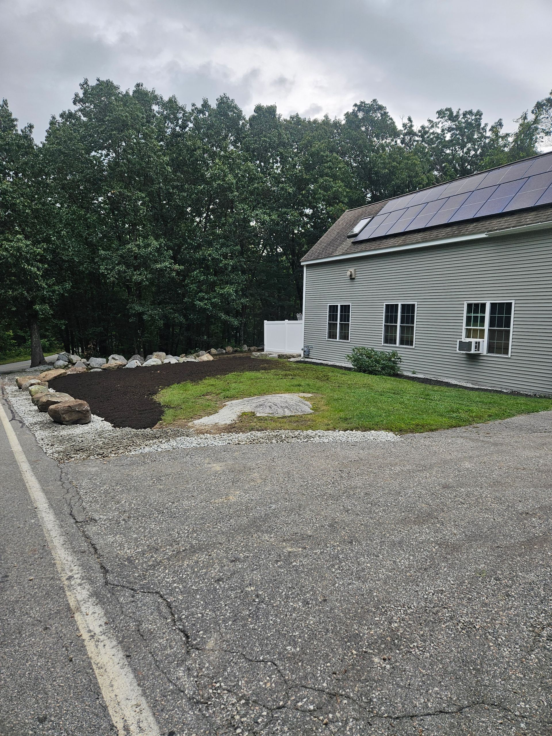 a house with solar panels on the roof is sitting next to a road