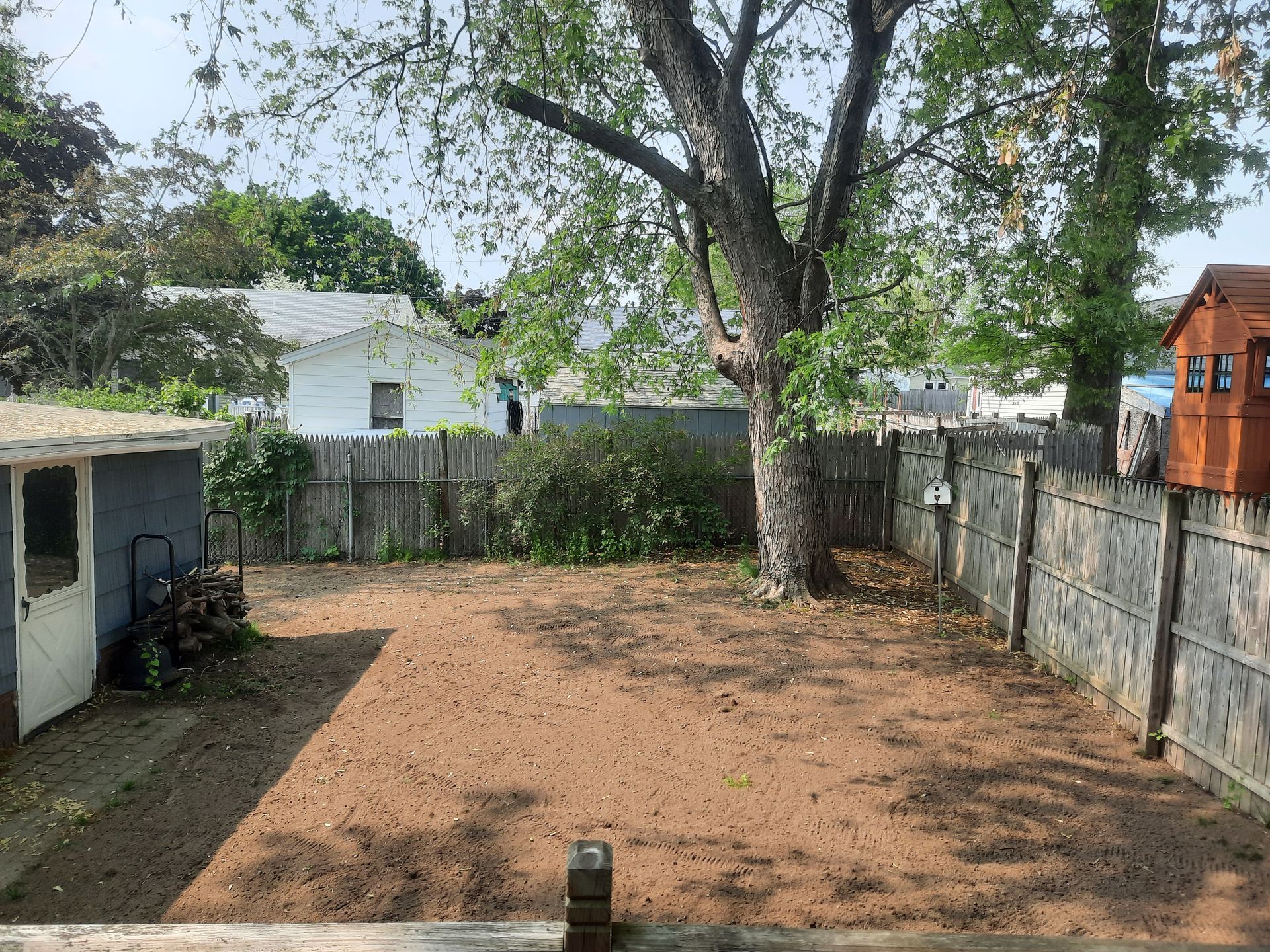 a backyard with a fence and a tree in the middle of it