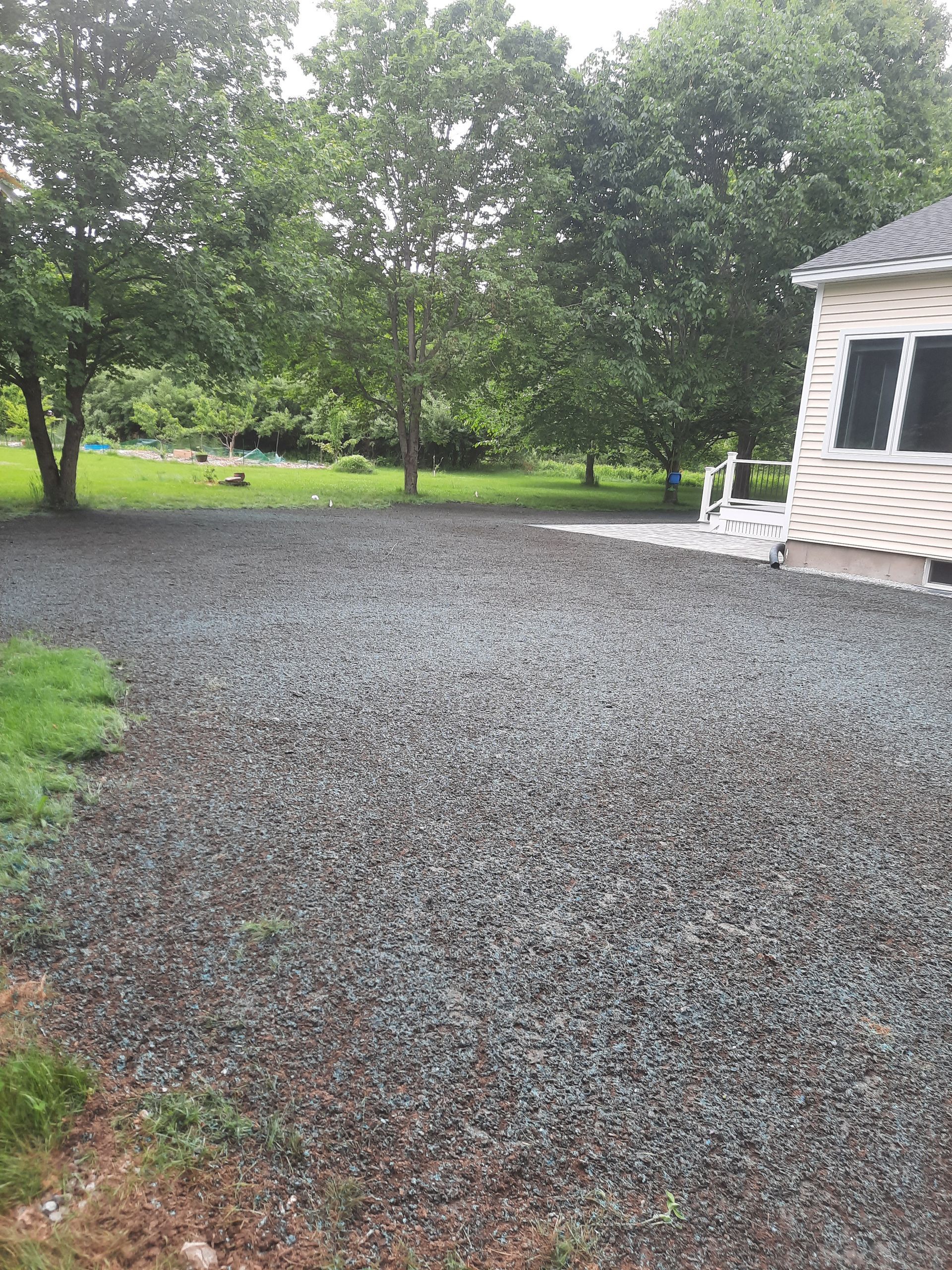 a gravel driveway leading to a house with trees in the background
