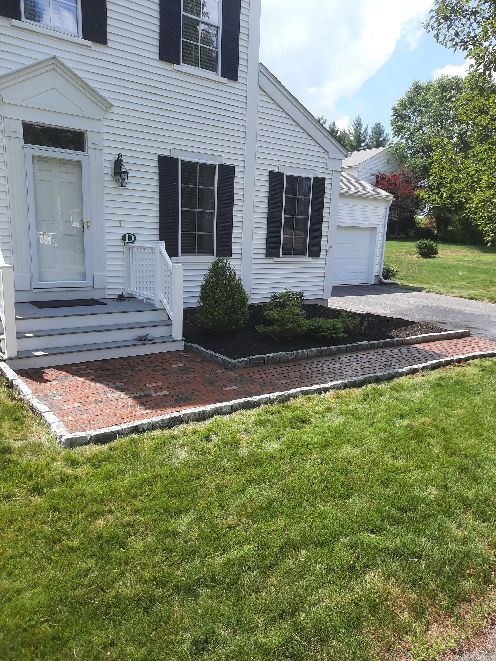 a white house with black shutters and a lush green lawn