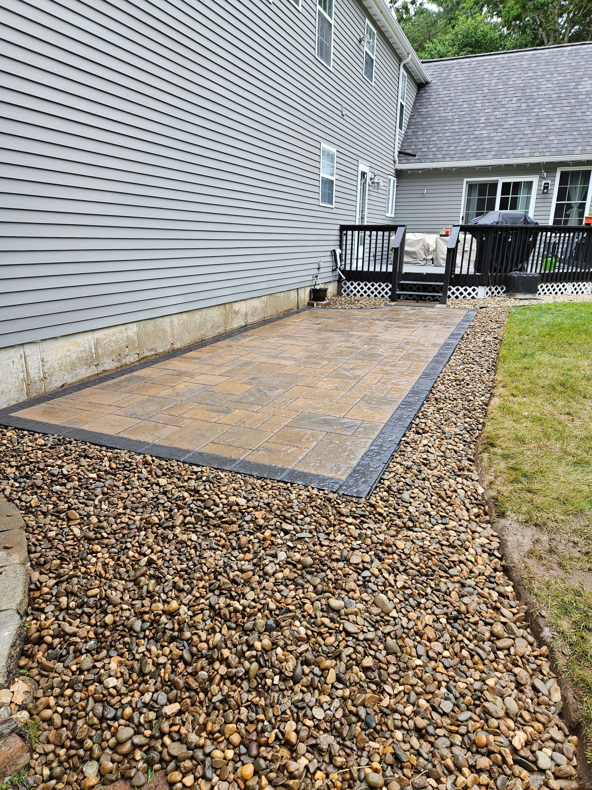 a stone walkway leading to a patio in front of a house