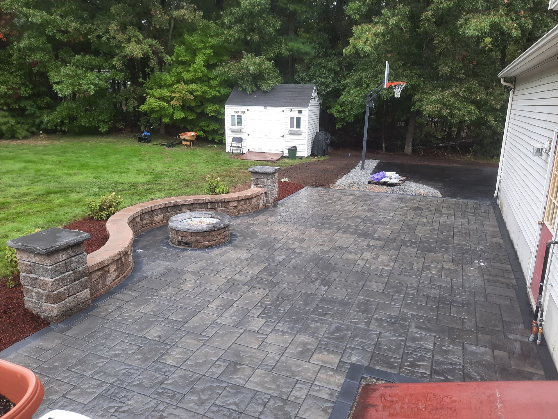 a patio with a fire pit and a basketball hoop in the backyard of a house