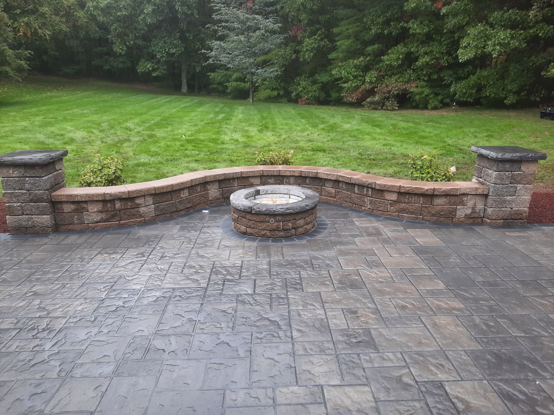 a brick patio with a fire pit in the middle of it
