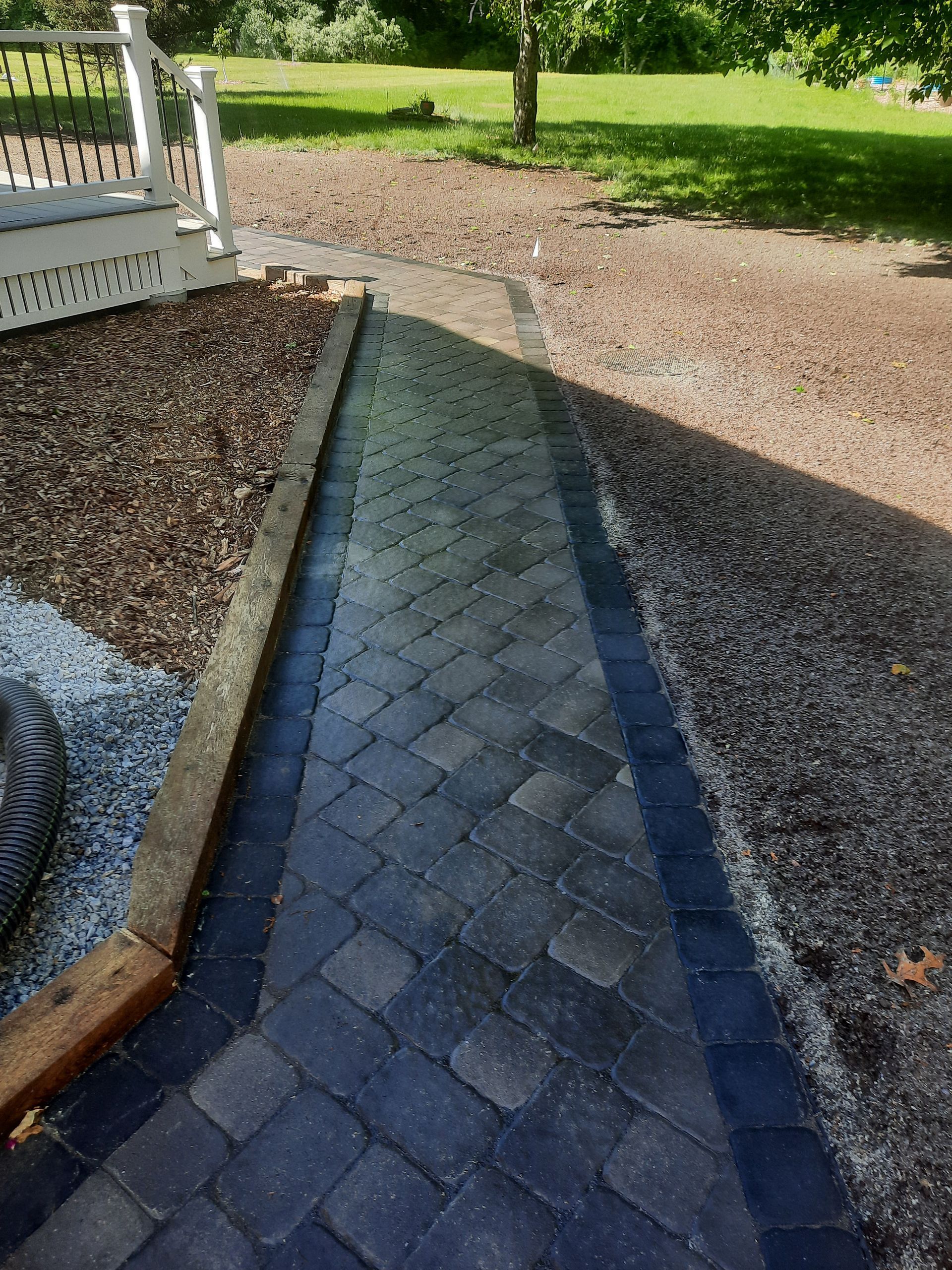 a brick walkway leading to a porch with a white railing