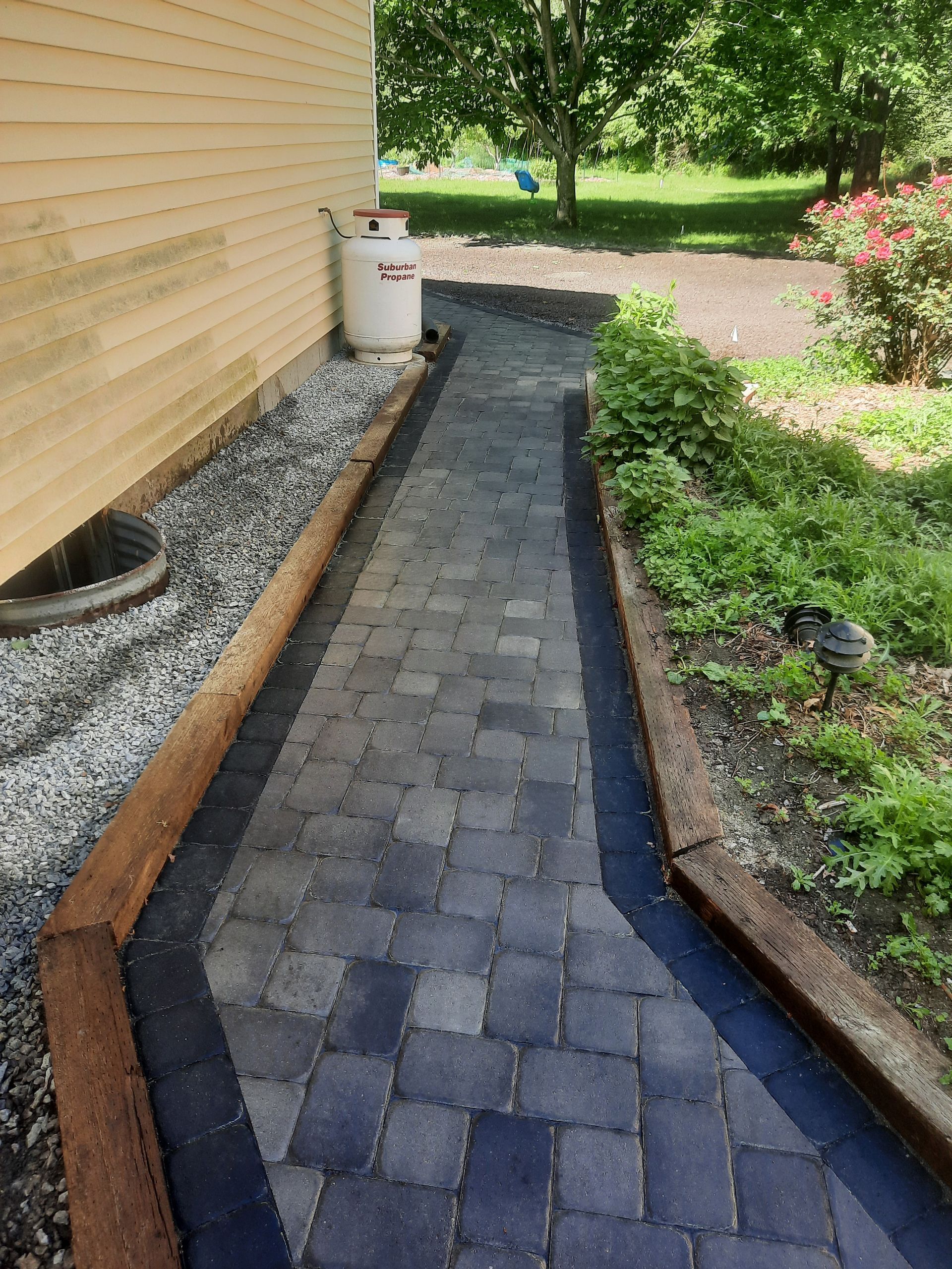 a brick walkway leading to a house next to a garden