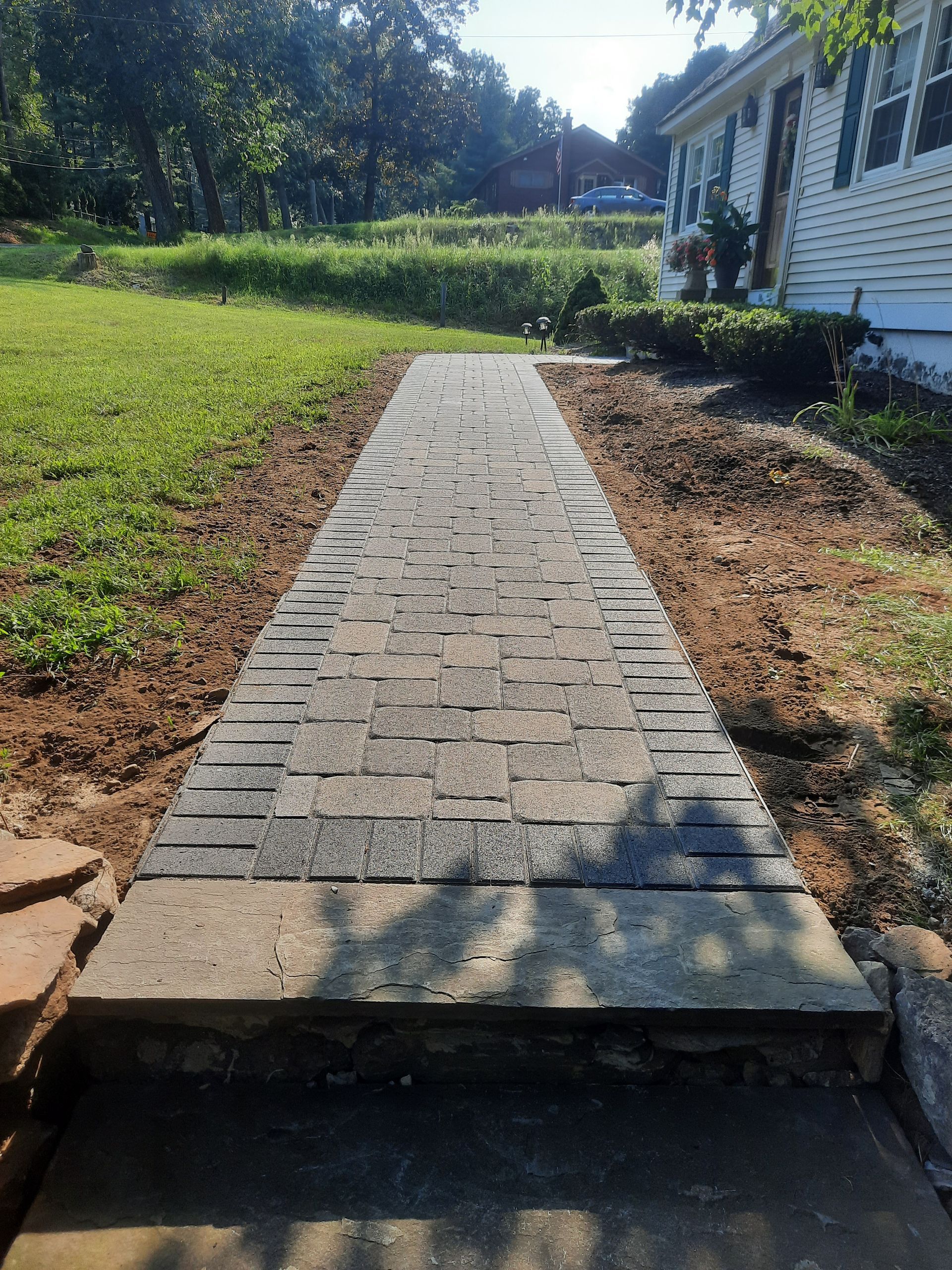 a brick walkway leading to a white house