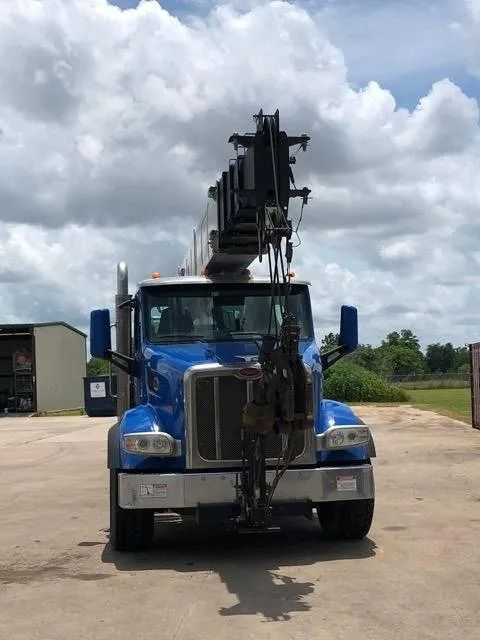 Blue crane truck parked, crane extended, against a cloudy sky.