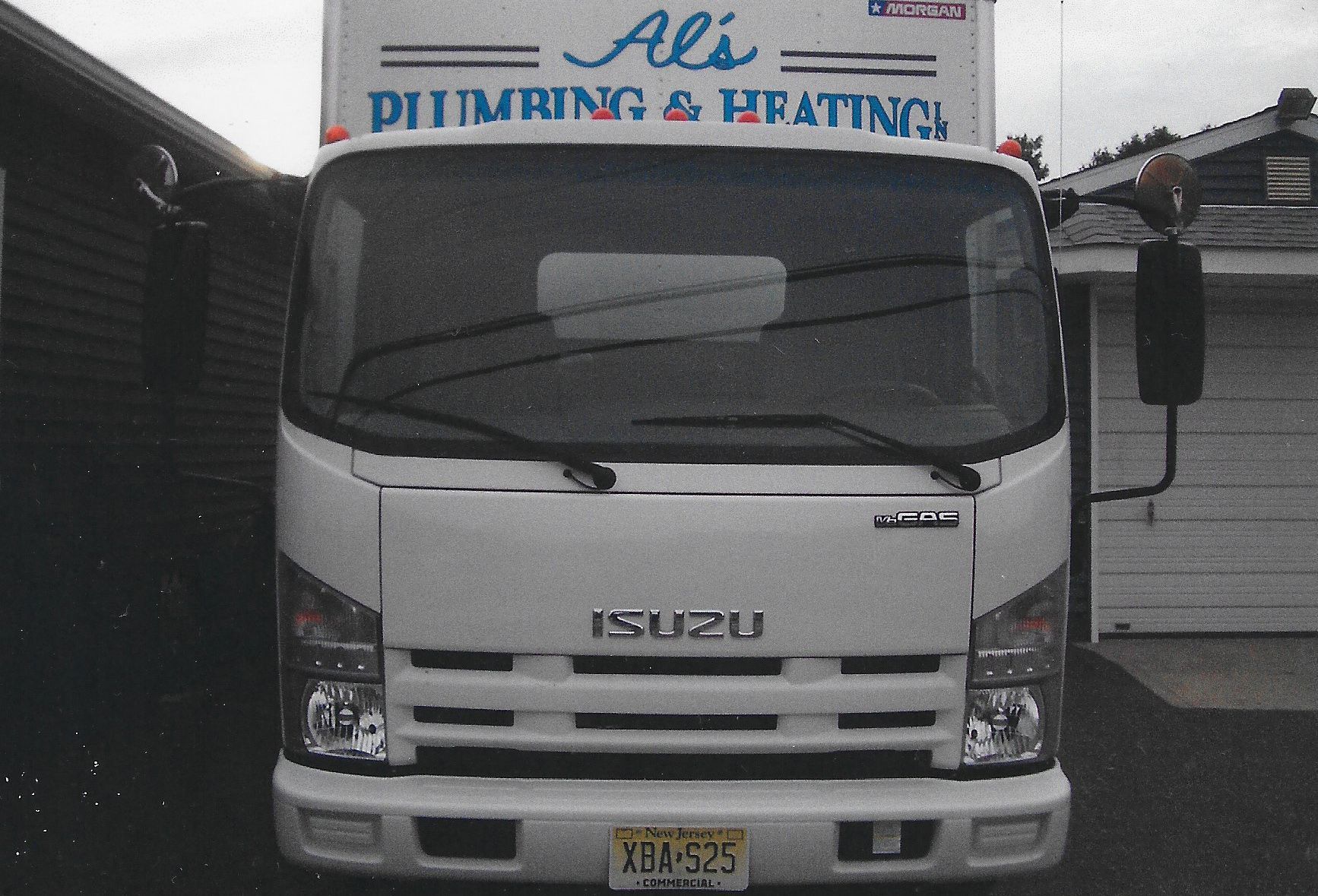A white Isuzu box truck parked outside with 