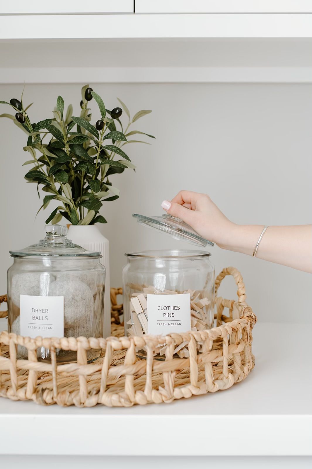 A person is holding the lid of a glass jar on a wicker tray