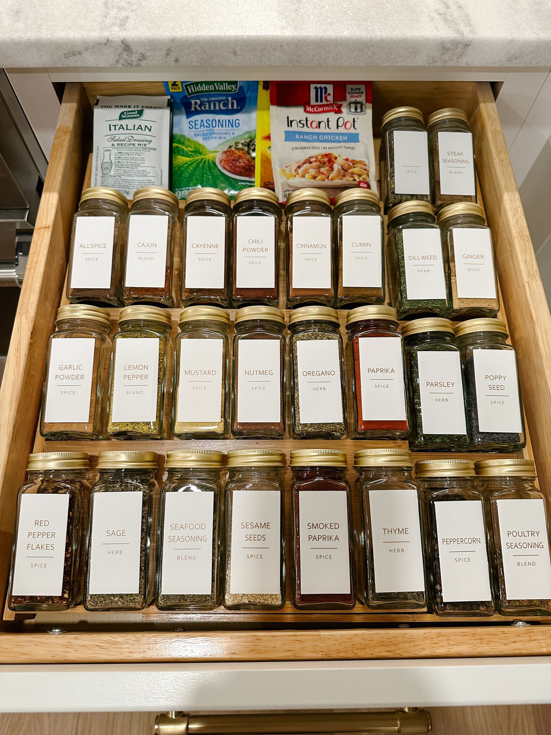 A drawer filled with jars of spices and packets of seasoning.