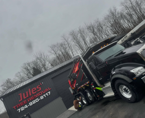 Tow truck beside a black pickup near a building with a “Jules” sign on a rainy day