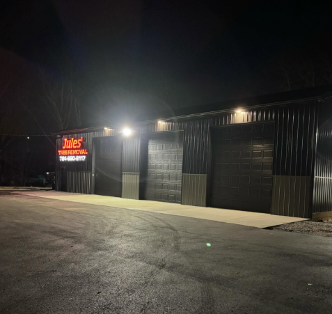 Dark warehouse at night with bright lights and an illuminated orange sign beside the lot