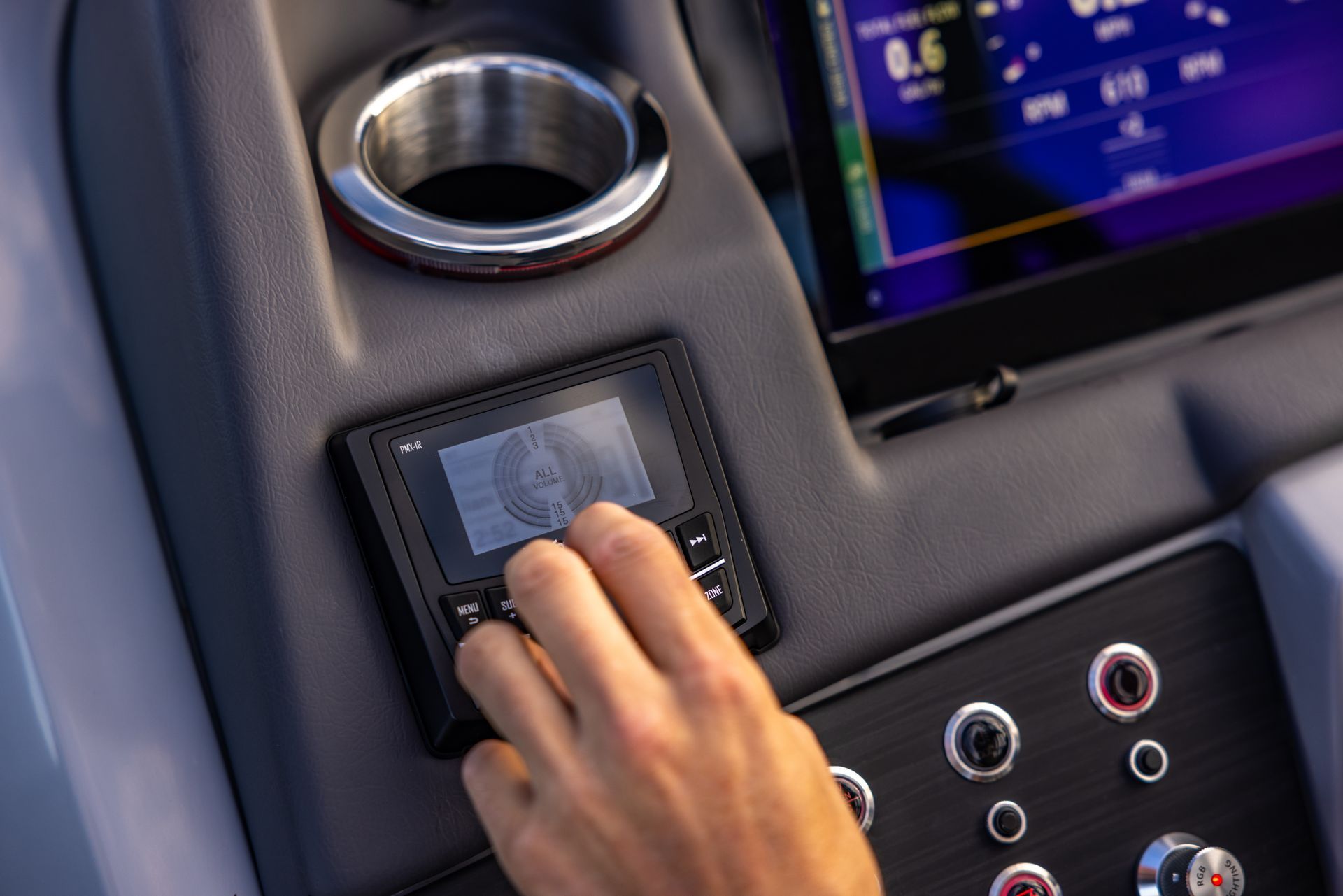 Hand adjusting a dashboard touchscreen in a car interior with circular vents and controls