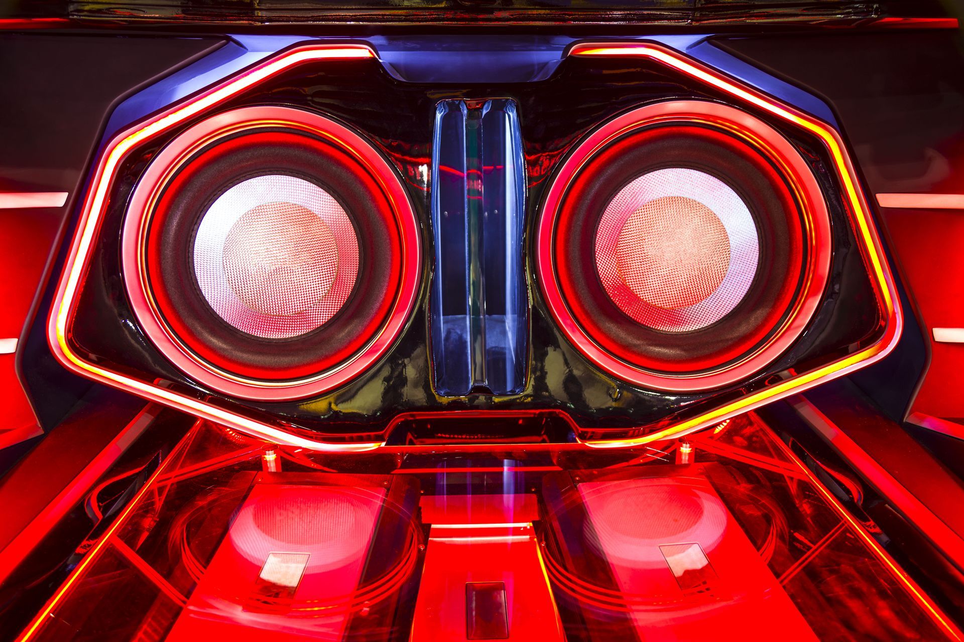 Red-lit car audio system with two large speakers. Illuminated with blue and red lights.