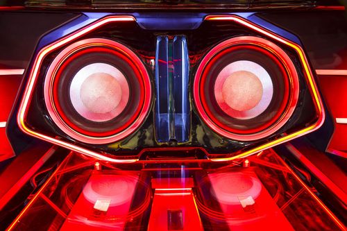 Red-lit car audio system with two large speakers. Illuminated with blue and red lights.