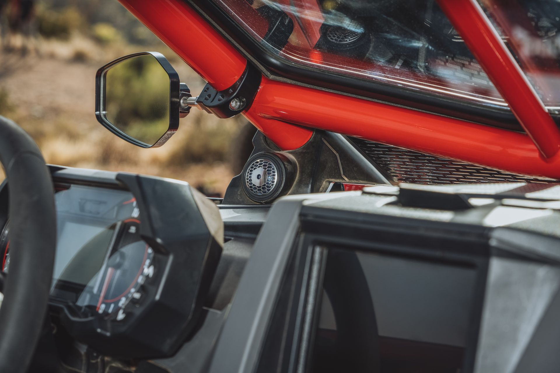 Motorcycle cockpit with red roll cage, mirror, and digital dashboard