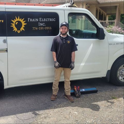 A man is standing in front of a frain electric inc. van