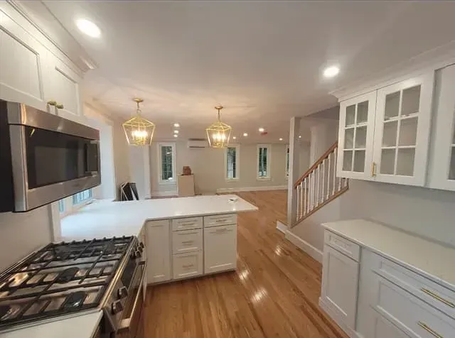 A kitchen with a stove, microwave, cabinets and hardwood floors.