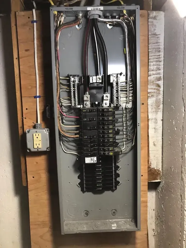 A large electrical box is hanging on a wooden wall.