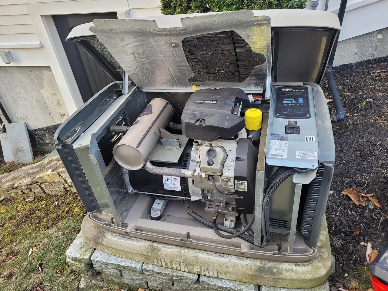 A generator is sitting on top of a concrete block with the hood open.