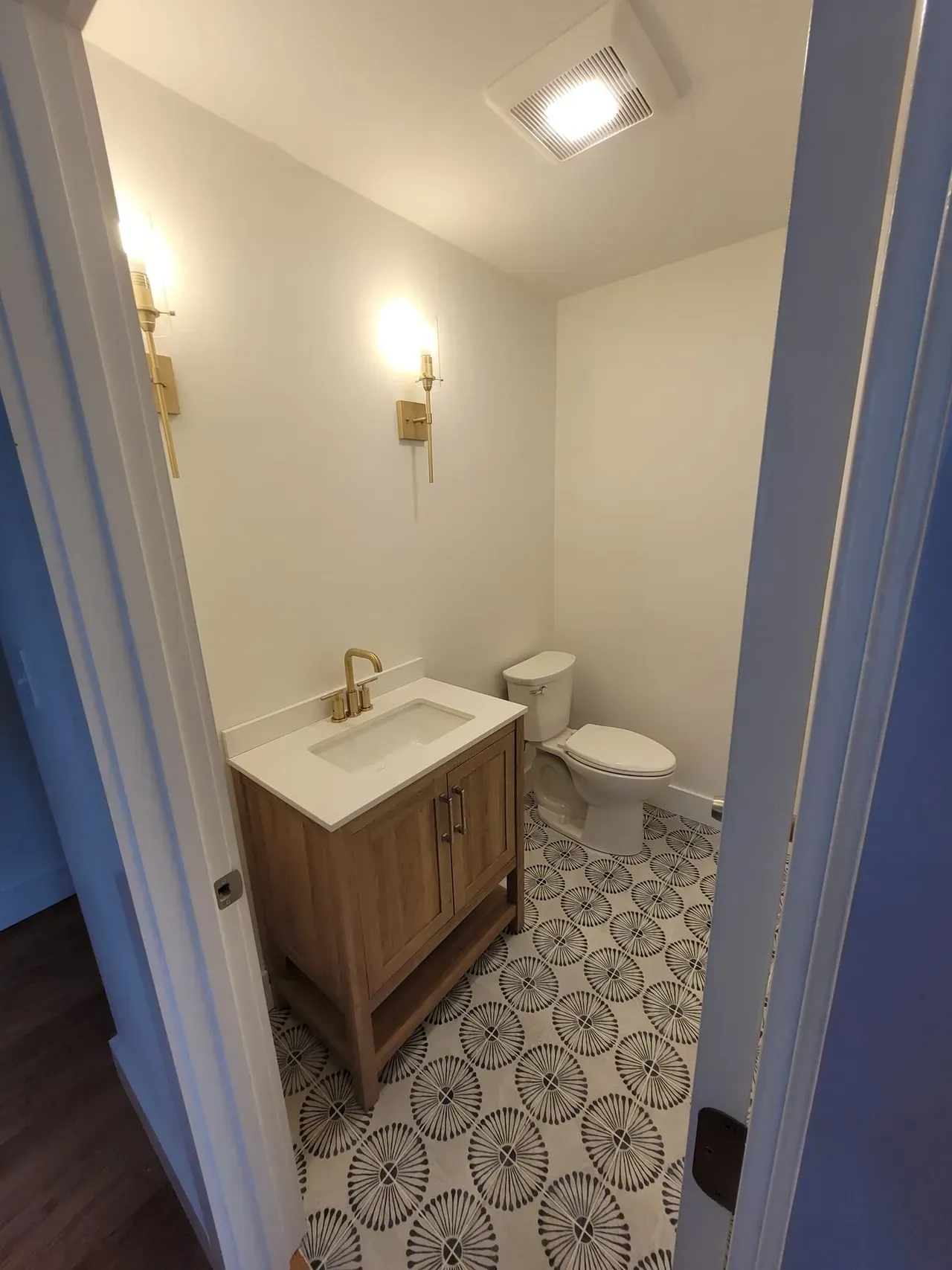 A bathroom with a sink, toilet, and tile floor.
