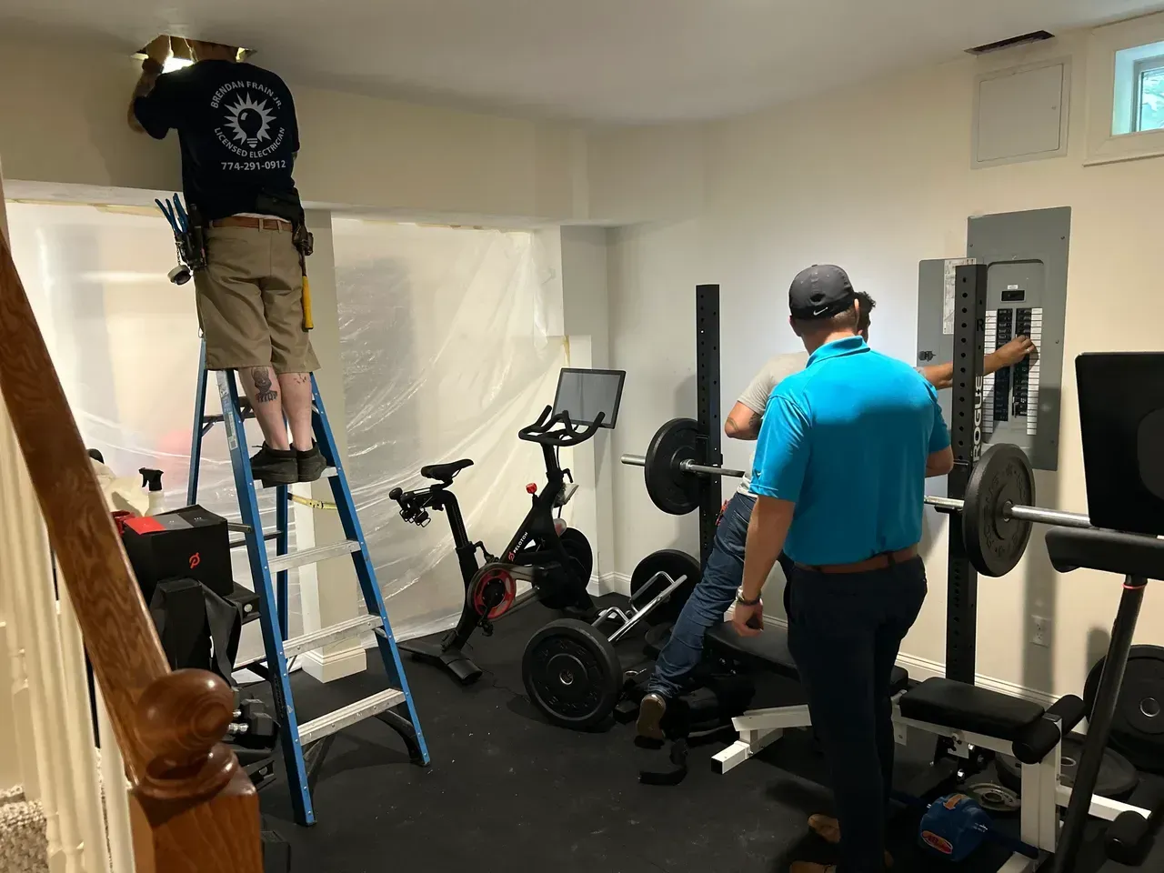 Two men are working on a gym in a basement.