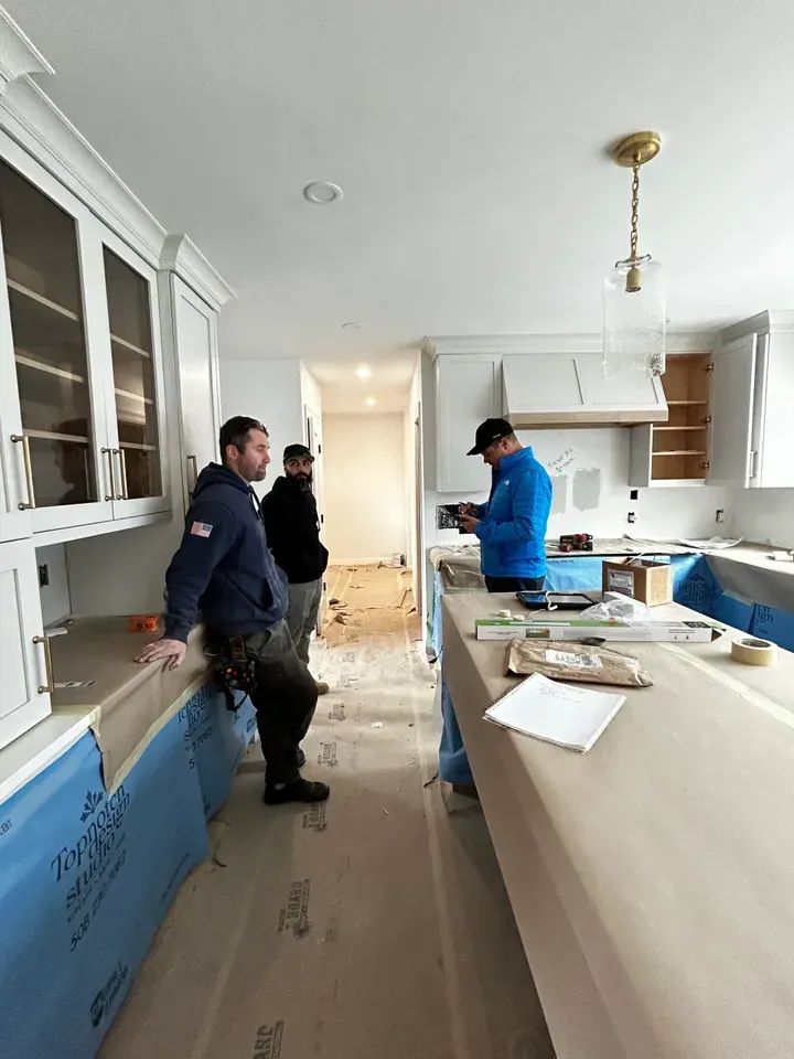 A group of men are standing in a kitchen under construction.