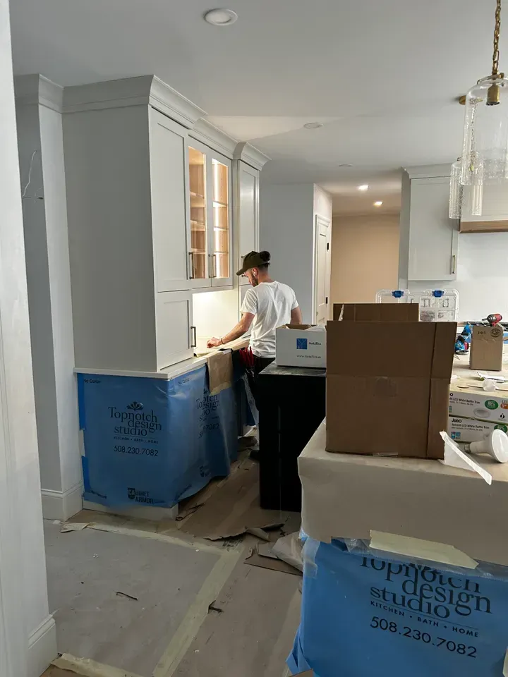A man is working in a kitchen with boxes on the floor.