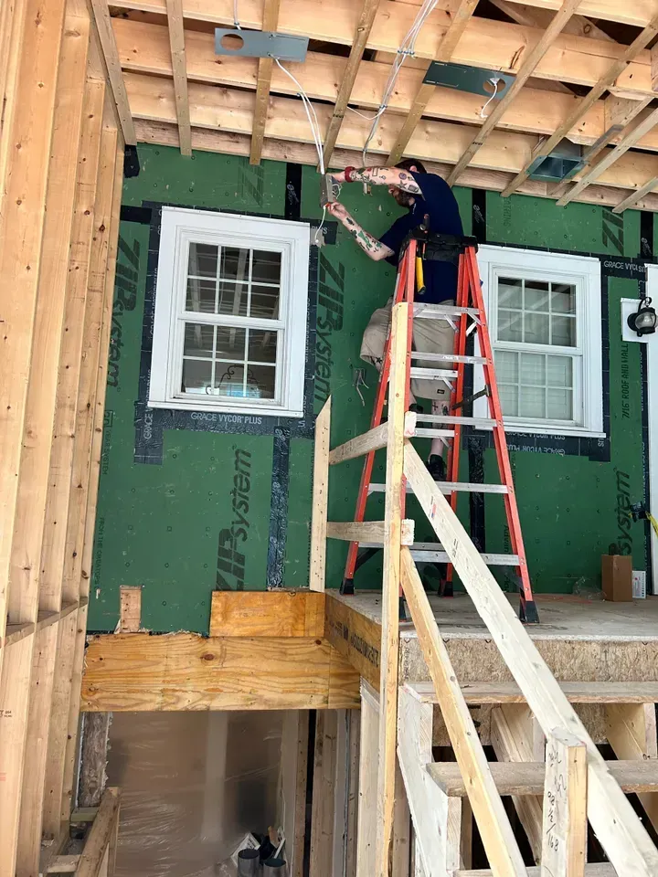 A man is standing on a ladder in a building under construction.