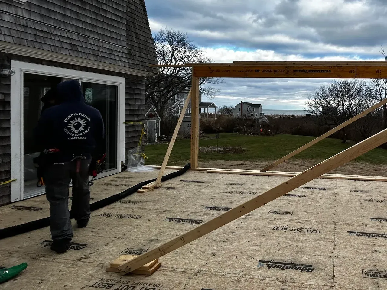 A man in a blue hoodie is standing in front of a building under construction.