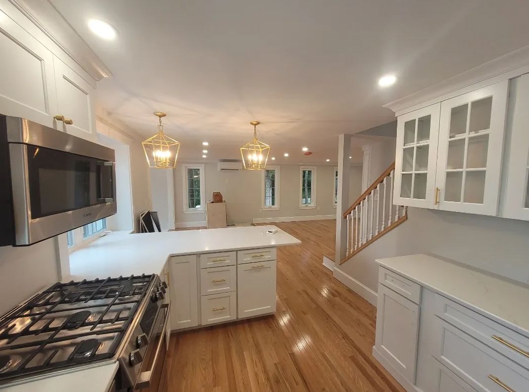 A kitchen with a stove, microwave, cabinets, and hardwood floors.