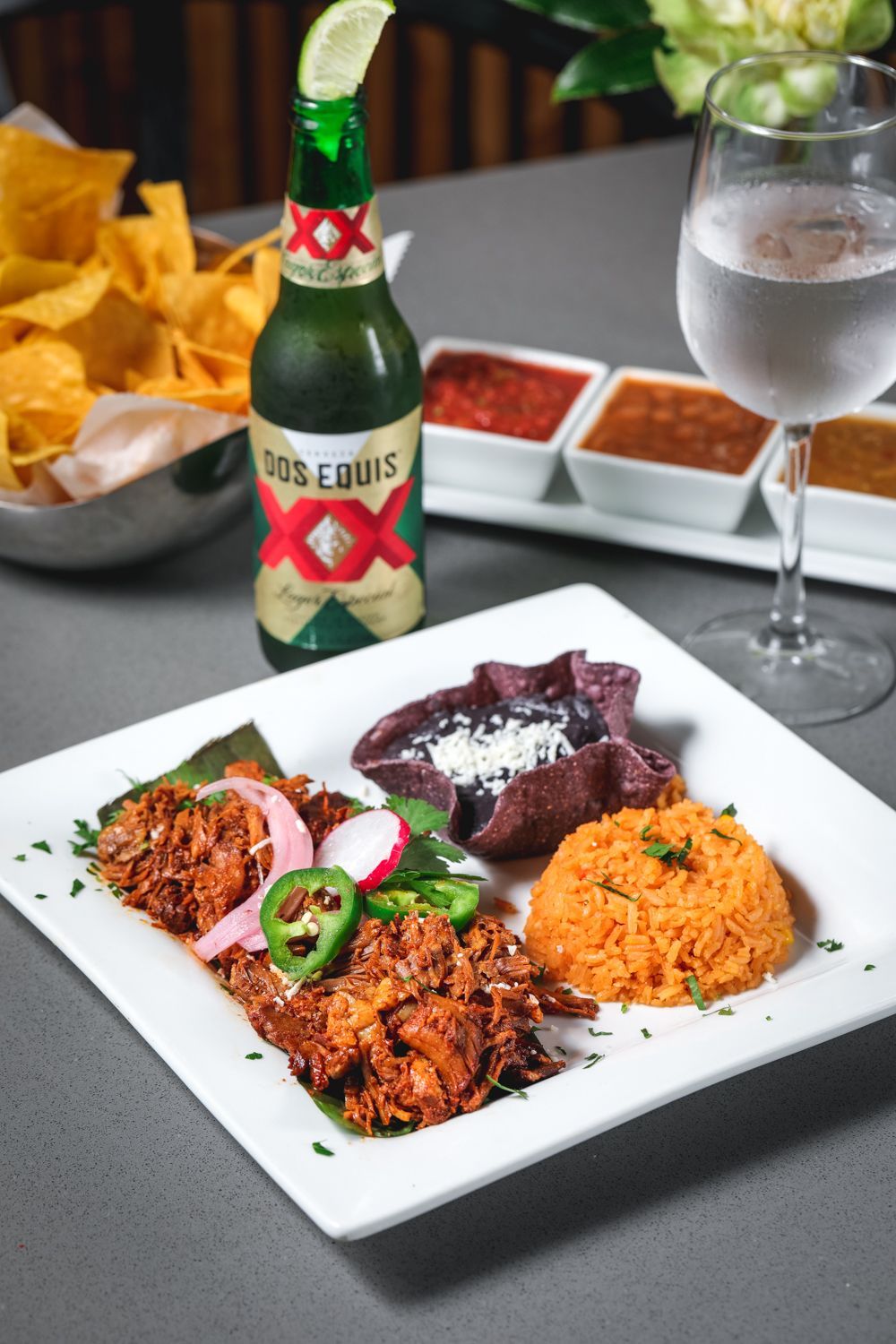 Mexican meal: shredded meat, rice, beans, salsa, chips, beer, water.