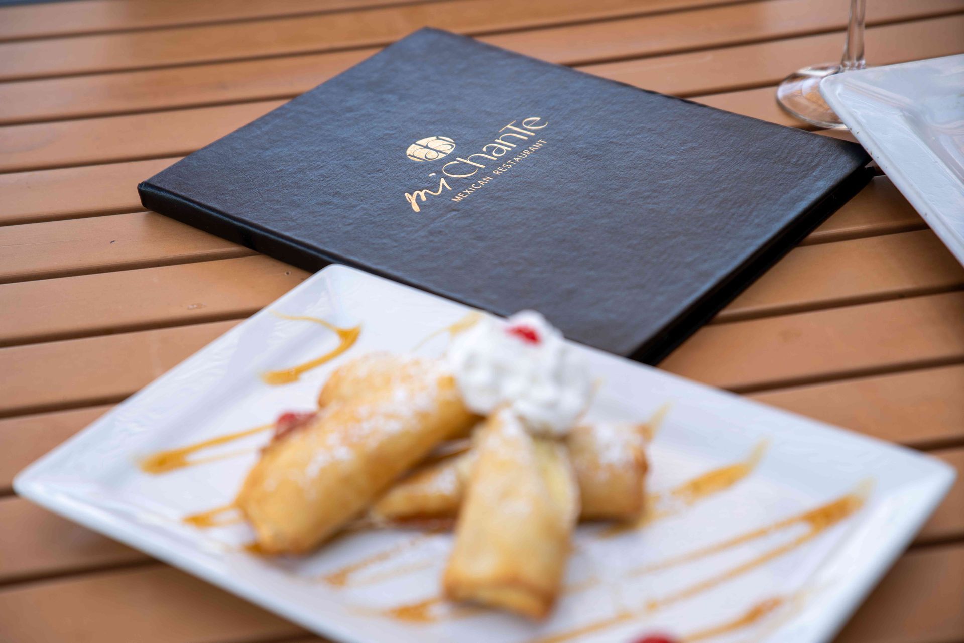 Dessert plate with fried pastries and whipped cream, restaurant menu on a table.