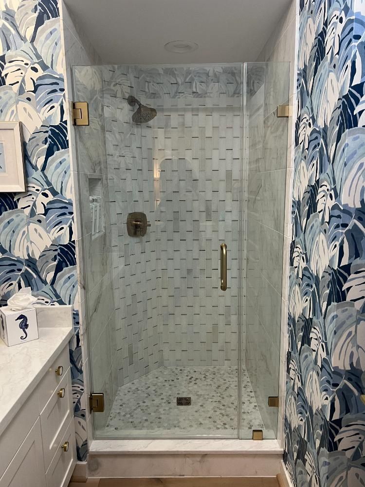 A bathroom with a walk in shower with a glass door.