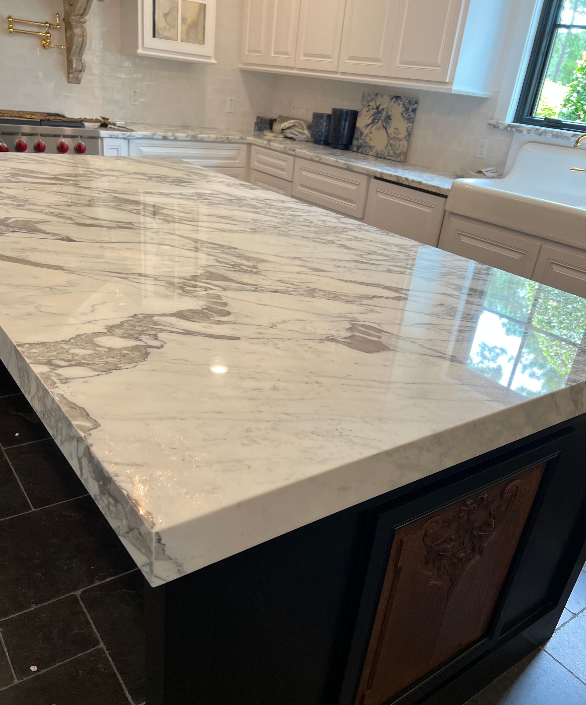 A kitchen with a large marble counter top and white cabinets.