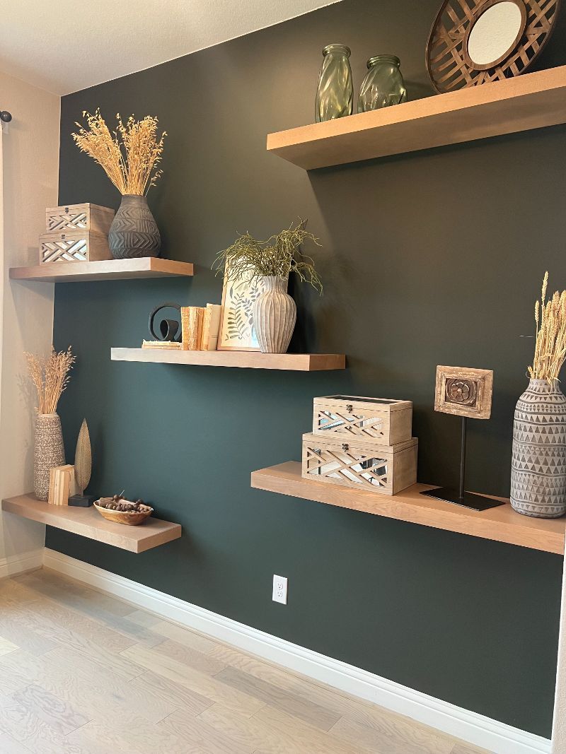 A living room with a black wall and wooden shelves.