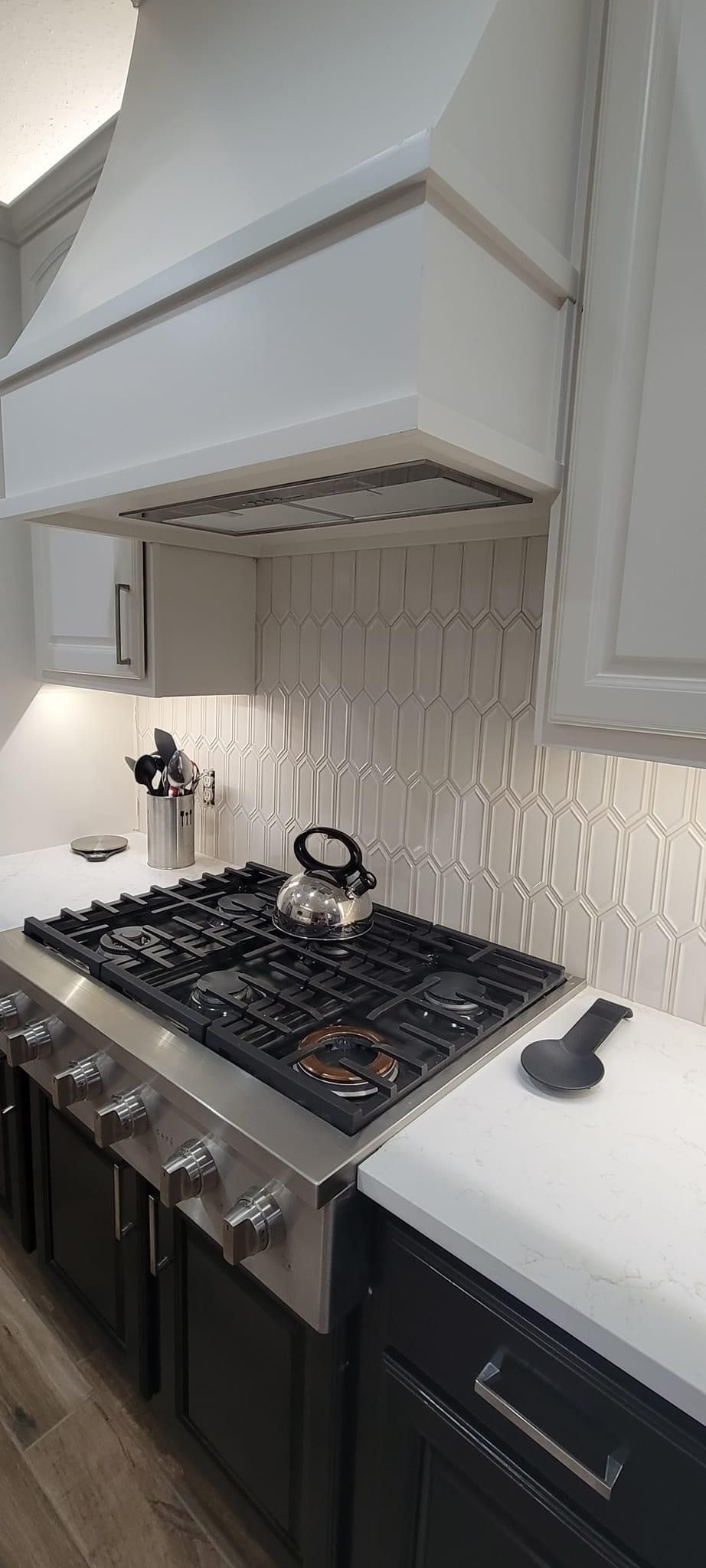 A kitchen with a stove top oven and a hood above it.