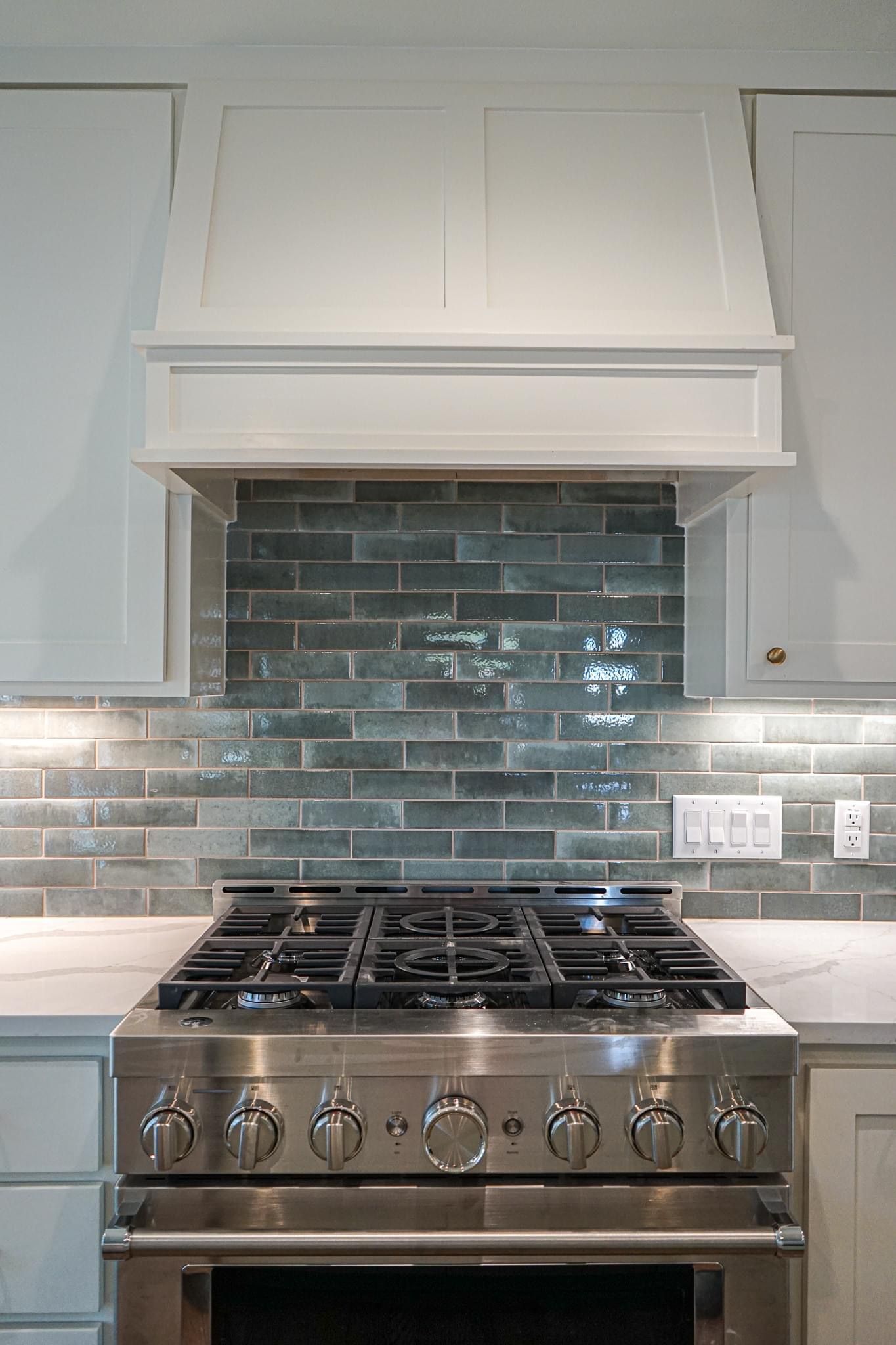 A kitchen with a stove top oven and a hood above it.