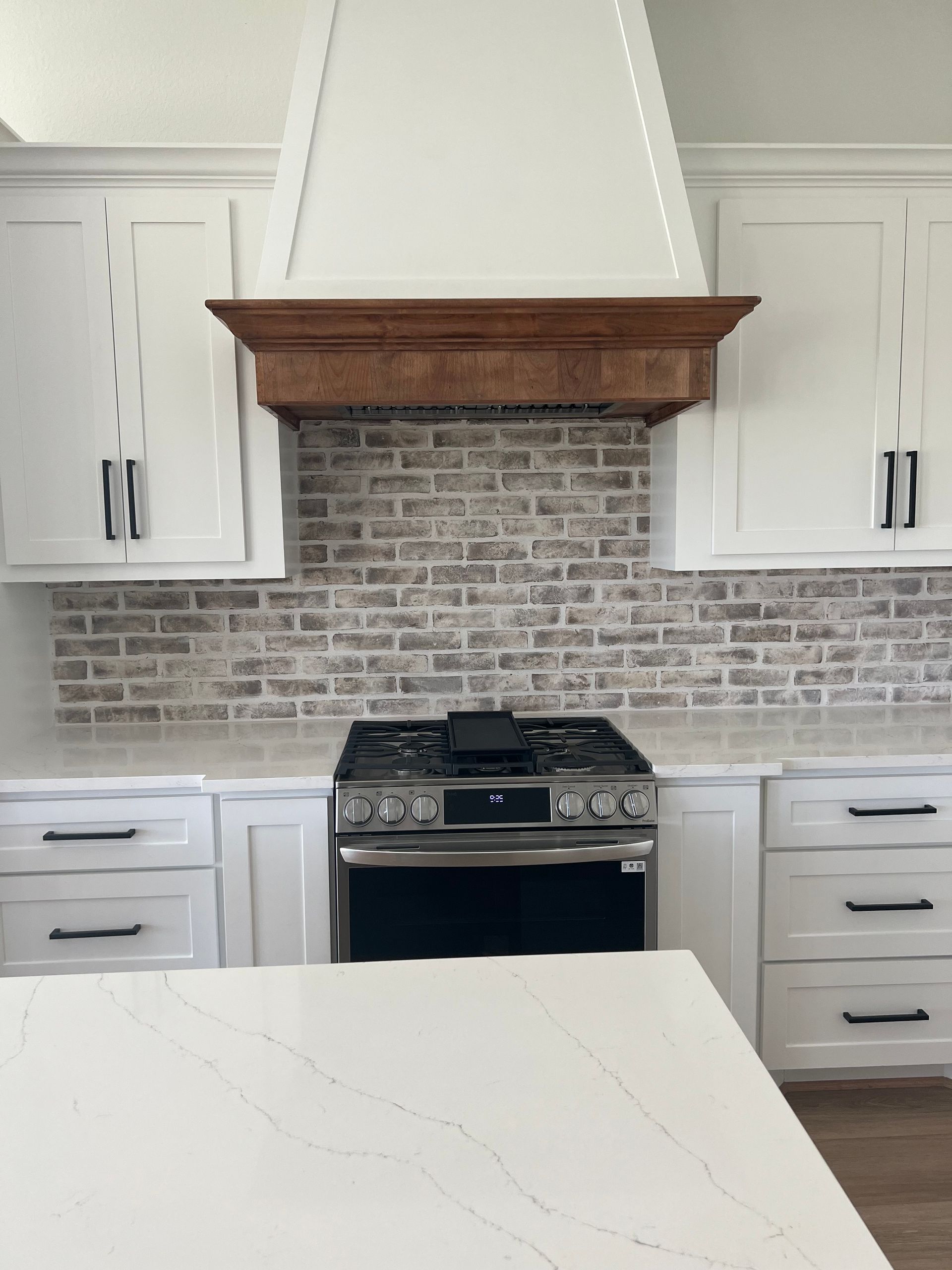 A kitchen with white cabinets and a stove top oven