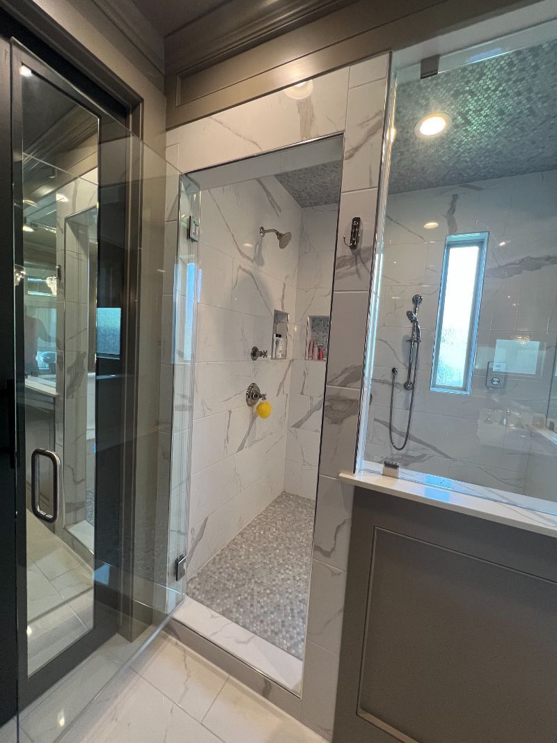 A bathroom with a walk in shower and a glass door.