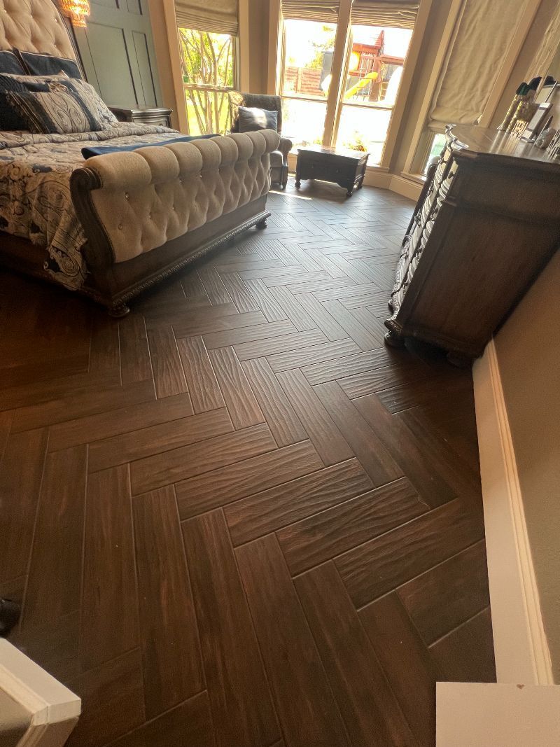 A bedroom with a bed , dresser , chair and stairs.