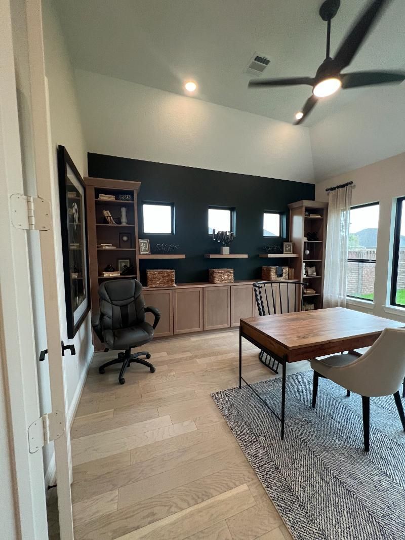 A home office with a desk , chair and ceiling fan.