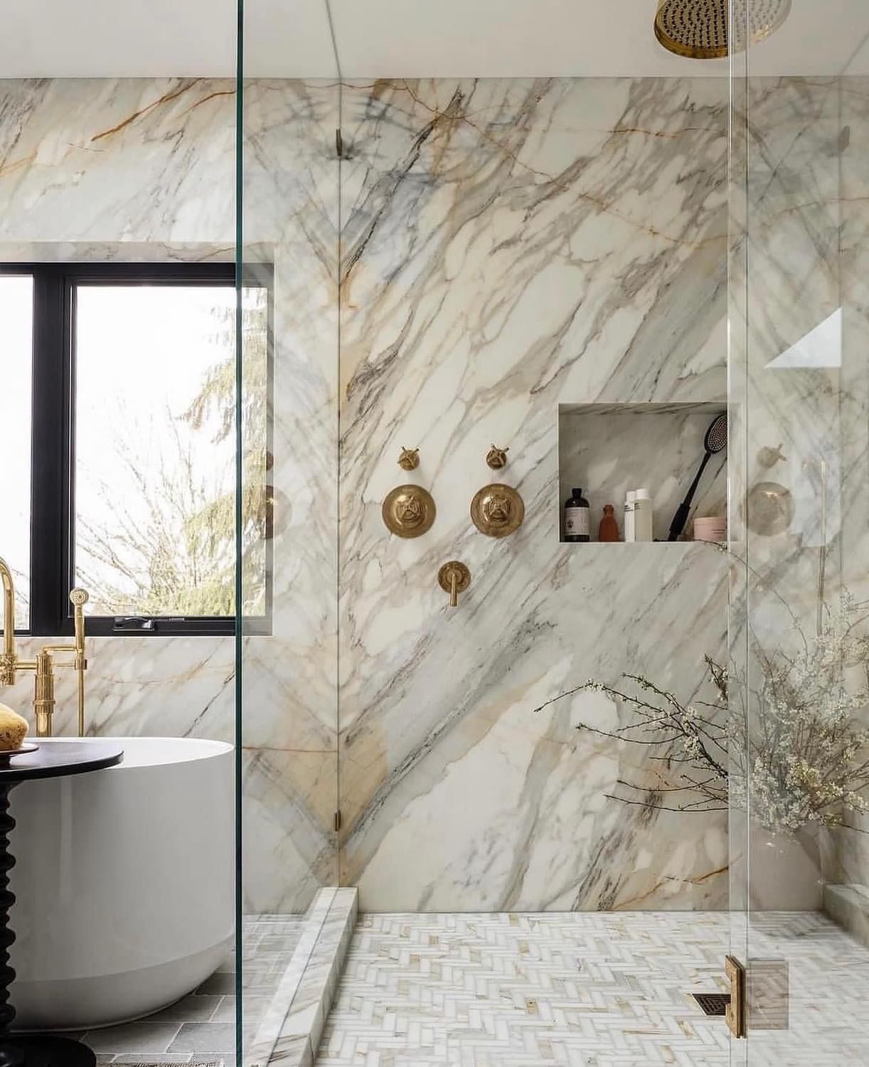 A bathroom with marble walls and a walk in shower