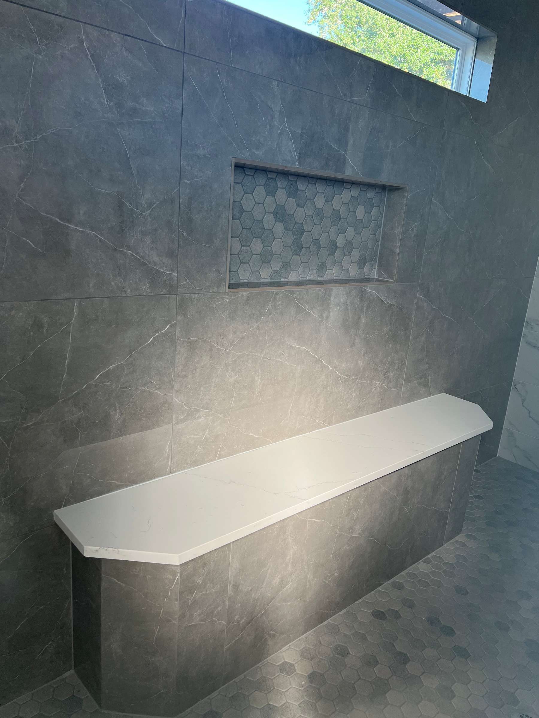 There is a bench in the shower with a window.
